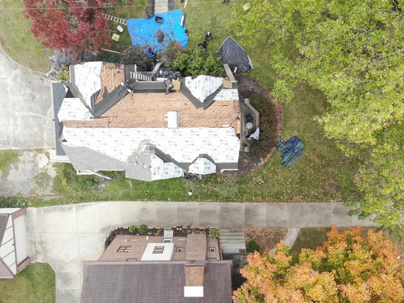 Drone view of a full roof replacement in progress on a large home